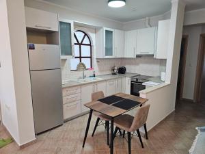 a kitchen with a table and a white refrigerator at Kouros Cozy Home II in Orestiada