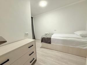 une chambre blanche avec un lit et une commode dans l'établissement Garden EVN Apartments, à Erevan