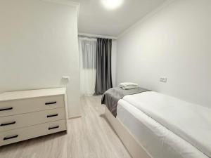 une chambre blanche avec un lit et une commode dans l'établissement Garden EVN Apartments, à Erevan 2 autres photos