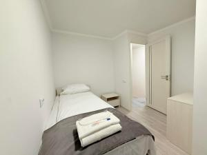 une chambre blanche avec un lit avec deux serviettes dessus dans l'établissement Garden EVN Apartments, à Erevan