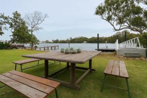 ein Picknicktisch mit zwei Bänken und ein Gewässer in der Unterkunft Waterfront Coomera Escape in Gold Coast