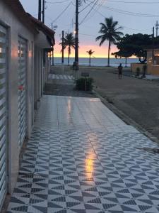 a stone walkway next to a beach at sunset at Linda Casa Mongagua COM 03 DORMS in Mongaguá