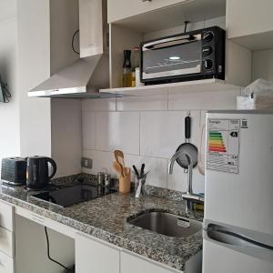 a small kitchen with a sink and a microwave at Departamento Los Carrera Centro in Osorno +10 photos