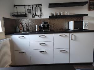 a kitchen with white cabinets and a microwave at Garden Home in Törökbálint