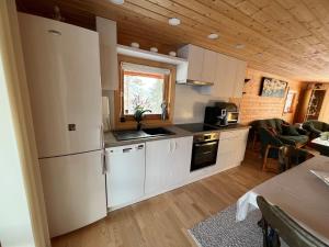 eine Küche mit weißen Geräten und ein Wohnzimmer in der Unterkunft Cozy Mountain Cabin in Senja in Senja