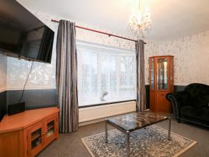 a living room with a tv and a glass table at Green Bank in Dymchurch