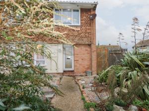 a brick house with a white door and a fence at Green Bank in Dymchurch