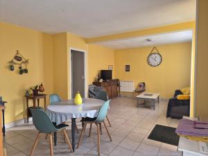 een woonkamer met een tafel, stoelen en een klok bij BRUYERE D'ANDAINE in Bagnoles de l'Orne