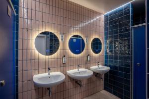 een badkamer met drie wastafels en spiegels op een betegelde muur bij Ideal Youth Hostel in Barcelona +58 foto's