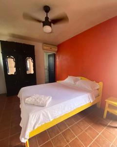 una camera con un letto bianco con una parete rossa di Hotel Pueblo Alegre a Huamboya