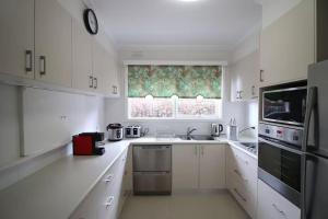 una cucina bianca con mobili bianchi e una finestra di Rosebud Comfort Retreat a Rosebud