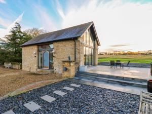 a stone cottage with a deck and a patio at The Lodge Lodge Farm in Bedford