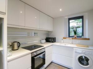 a kitchen with white cabinets and a washer and dryer at The Lodge Lodge Farm in Bedford