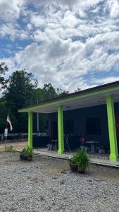 a blue building with green columns and plants in front at D'pinggir Guest Room in Kuala Tahan