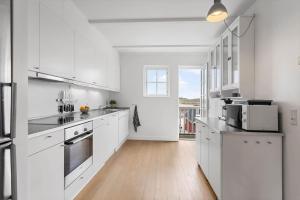 a white kitchen with white cabinets and a wooden floor at LL264-Bagenkop-Faergevej-9-1-th in Bagenkop