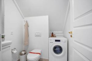 a white bathroom with a washing machine and a toilet at LL264-Bagenkop-Faergevej-9-1-th in Bagenkop