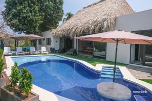 a villa with a swimming pool and an umbrella at Cala los Mangos in Tamanique