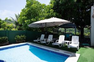 a group of chairs and an umbrella next to a pool at Cala los Mangos in Tamanique