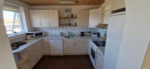 una piccola cucina con armadietti bianchi ed elettrodomestici bianchi di Fihermans House Joanna2 a Hirtshals Altre 3 foto