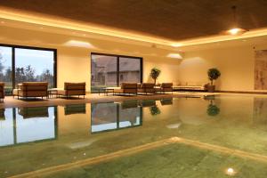 een leeg zwembad in een hotel met stoelen en tafels bij Farmer Hotel Basedow & Spa in Basedow