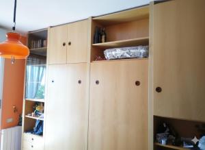 a kitchen with wooden cabinets and an orange lamp at Condominio Ariazzurra S. Bart. in San Bartolomeo al Mare +25 photos