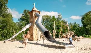 two children playing on a slide at a playground at Stacaravan Camping It Wiid Earnewoude in Earnewâld