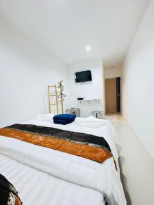 a large bed in a white room with a tv at Patong Beach Verve in Patong Beach