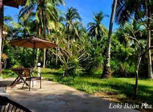 een tafel en een parasol op een patio bij Loki Baan Paa in Ko Kood +25 foto's