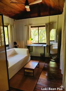 een woonkamer met een witte bank en een tafel bij Loki Baan Paa in Ko Kood