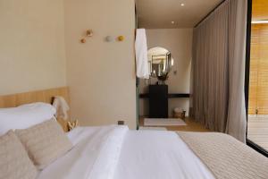 a bedroom with a white bed and a mirror at Bowi Hotel Conceito in Tiradentes