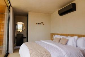 a bedroom with a large bed with white sheets at Bowi Hotel Conceito in Tiradentes
