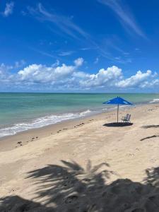 een blauwe parasol en stoelen op een strand bij Flats Privativos MaragoJulios in Maragogi