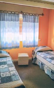 twee bedden in een kamer met oranje muren en ramen bij Duplex Gesell in Villa Gesell +13 foto's