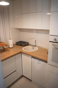 een witte keuken met een wastafel en een aanrecht bij Apartman Nana in Vranje