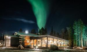 a cabin with the aurora above it at night at Vaattunki Wilderness Resort in Rovaniemi