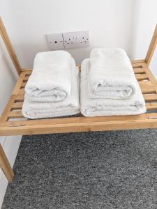 two white towels on a wooden shelf in a room at St Davids House in Cranbrook