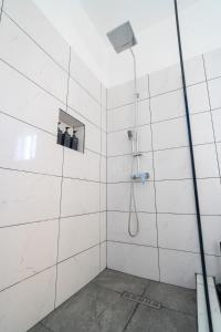 een badkamer met een douche en witte betegelde muren bij Luxury Apt with Amazing Views in Saint Johnʼs