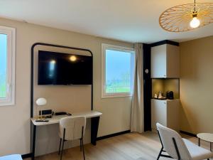 een kamer met een bureau en stoelen en een keuken bij Brit Hotel Saint-Méen-le-Grand en Brocéliande in Saint-Onen-la-Chapelle