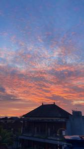a building with a sunset in the sky at Mars Homestay Ubud in Ubud