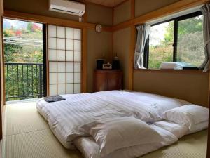 a large white bed in a room with windows at 箱根宿燕帰 in Hakone