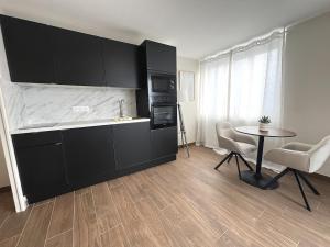 eine Küche mit schwarzen Schränken sowie einem Tisch und Stühlen in der Unterkunft L'Hakuna II - Suite et Spa in Fontaine-Notre-Dame + 24 Fotos