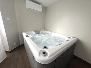 una vasca da bagno bianca con acqua blu in camera di L'Hakuna II - Suite et Spa a Fontaine-Notre-Dame