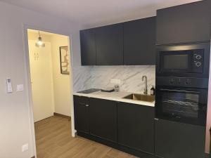 una cucina con armadi neri, lavandino e forno a microonde di L'Hakuna II - Suite et Spa a Fontaine-Notre-Dame Altre 24 foto