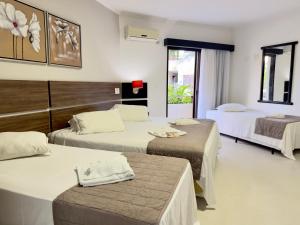 a hotel room with three beds in a room at Pousada Larimor in Boicucanga +101 photos