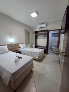 a hotel room with two beds and a television at Rede Andrade Porto Mar in Maceió