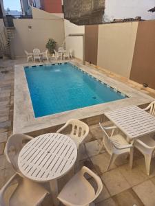 a pool with chairs and a table and a table and chairs at Rede Andrade Porto Mar in Maceió