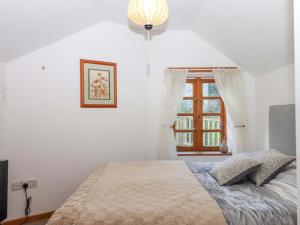 a white bedroom with a bed and a window at Park Cottage in Kingsbridge