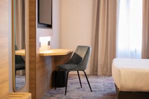 a bedroom with a chair and a desk and a bed at Brit Hotel Cahors Centre - Le Valentre in Cahors
