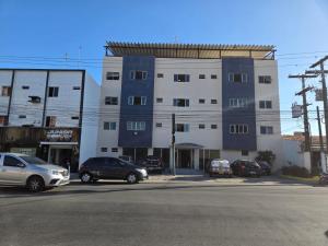 a building with cars parked in a parking lot at Rede Andrade Porto Mar in Maceió
