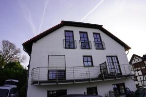 ein weißes Haus mit schwarzen Fenstern und einem Balkon in der Unterkunft Panoramablick, ruhiger Lage, 20 Min nach Köln - EVARIS Hilda in Overath